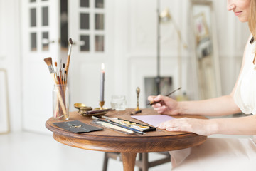A copywriter writes a story. A hand is holding a ink pen in front of a blank sheet. Free space for...