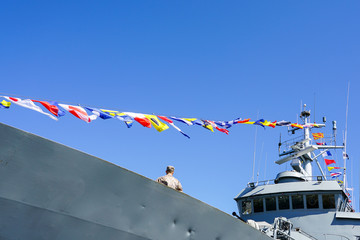 a gray warship fragment decorated with a row of colorful nautical flags