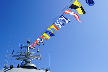 a gray warship fragment decorated with a row of colorful nautical flags © Zigmunds