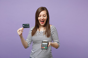 Naklejka premium Woman in casual clothes isolated on violet background studio portrait. People lifestyle concept. Mock up copy space. Hold wireless modern bank payment terminal to process acquire credit card payments.