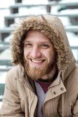 A bearded young man walks on winter street