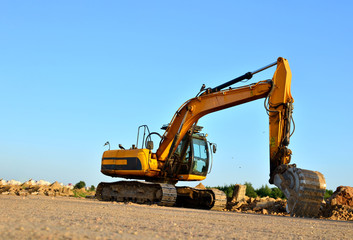 Fototapeta na wymiar Excavator at a construction site during earthworks and laying of underground pipes. Professional excavation contractor serving, trenching, grading for residential, commercial, and municipal projects