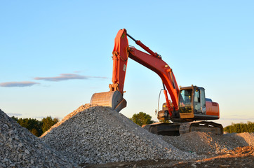 Large tracked excavator works in a gravel pit. Loading of stone and rubble for its processing at a concrete factory into cement for construction work. Cement production factory on mining quarry