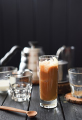 Iced coffee with cream in tall glass on black background copy space