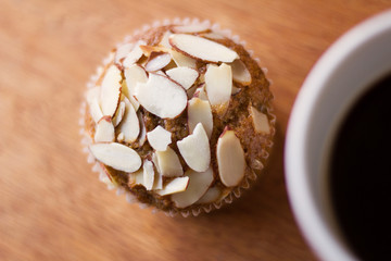 Fresh almond flavored cupcake on a table with a cup of coffee. Cenital view