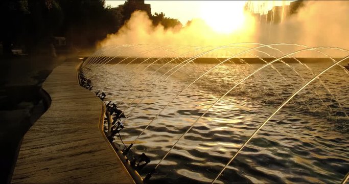 City water fountain spreading mist in the sunset light - evening scene in Bucharest, Romania, at the Bucharest Artesian Fountains (Fantana lui Bucur). 4K DCI.