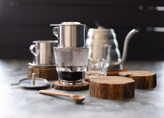 Vietnamese black drip coffee. Traditional Vietnamese coffee maker phin and goose neck kettle on...