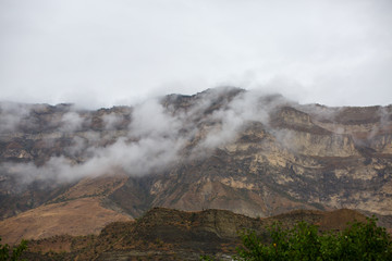 Photo of mountains with green vegetation, smoke above tops of day