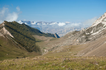 Fototapeta premium Image of mountain area with blue clear sky, green field on summer