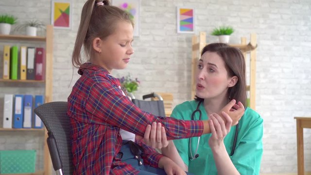 doctor examines the hand of a teenage girl in a wheelchair after an injury close up