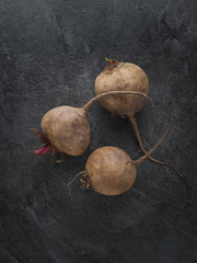 Three fresh ripe beetroots on dark table. Overhead shot.