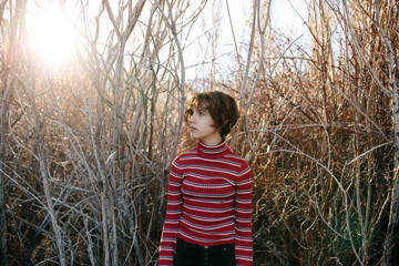 Teen girl wearing a turtleneck standing in front of a wooded area
