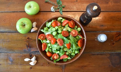 green and red salad in a round rustic plate on a wooden table