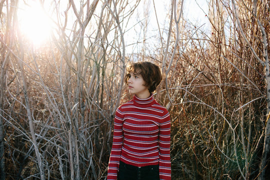 Teen girl wearing a turtleneck standing in front of a wooded area