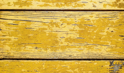 wooden old boards painted with yellow paint that has already cracked and peeled off