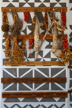 Tomatoes, garlic and herbs drying on a traditionally decorated wall.