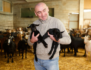 Positive farmer with goatlings on his hands