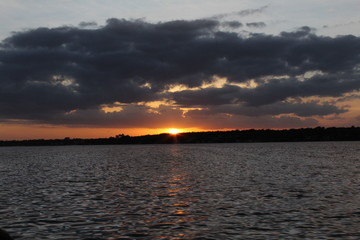 atardecer en laguna  con nubes y sol 