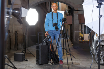 Portrait of cheerful photographer with his camera during photo shooting on town street