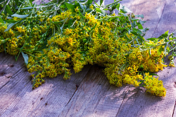 Hypericum flowers on the background of an old wooden table.