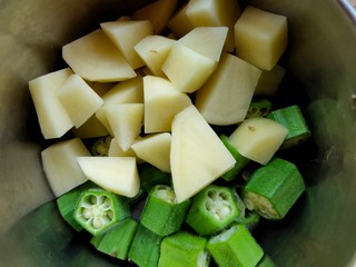 fresh vegetables ladies finger , potatoes cut up slices for making curry India in bowls