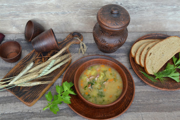 Pea soup with bacon and potato in wooden bowl on rustic table