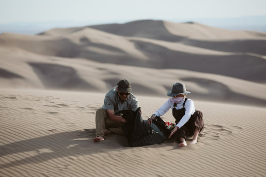 two adventurers take shelter from the whipping wind of the sand dunes