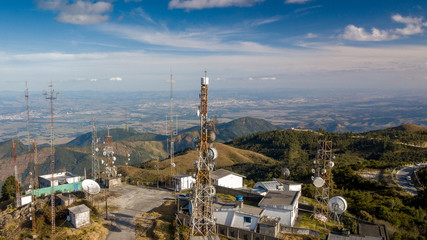 Telecommunications tower, antenna and satellite dish and aerial view of the city as background, sunset.