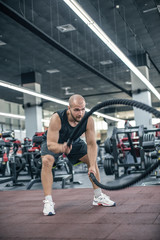 Fototapeta na wymiar Man with battle rope battle ropes exercise in the fitness gym. 
