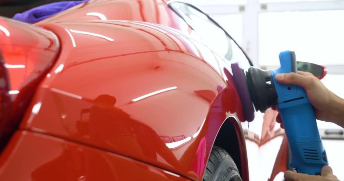 In the car center (in the garage), professionals polish a new sports car. Luxury car polishing. Concept of: Racing, Sport car, New, Slow motion, Nascar, Red, Chrome plated.
