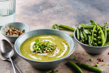 Green pea soup with croutons and micro greens sprouts on brown background