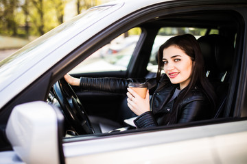Obraz na płótnie Canvas Young beauty woman in formal wear driving a car and holding a cup of coffee