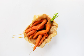 Ugly carrots in a box on a white background. Ugly food concept, top view.