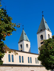 Fototapeta premium A peaceful landscape in the region of Medjugorje, Bosnia and Herzegovina, with the towers of the church of St. James in the distance.