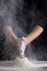 The cooking process, hands on a black background, flour. Confectioner