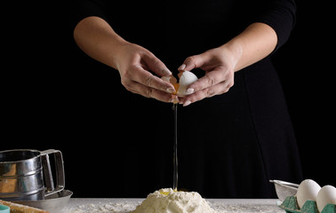 The cooking process, hands on a black background, flour. Confectioner