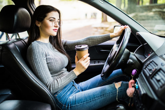 Happy Young Woman With Coffee To Go Driving Her Car In The Morning