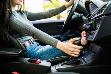 Young woman shifting gears on gearbox and driving car