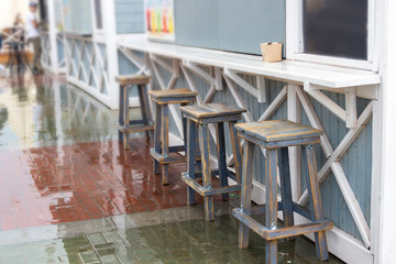 Wooden furniture on a wooden deck on the sidewalk near cafe and restaurant with nobody around during a morning time