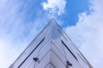 Skyscraper, Fragment of the facade of abstract modern commercial architecture, the corner of the walls under a blue cloudy sky