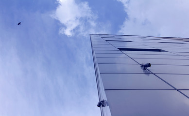 Obraz premium Skyscraper, Fragment of abstract modern commercial architecture, the angle of the walls of metal under a blue cloudy sky