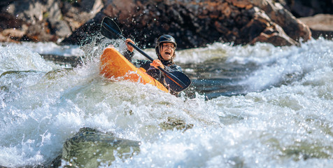 Guy in kayak sails mountain river. Whitewater kayaking, extreme sport rafting - obrazy, fototapety, plakaty