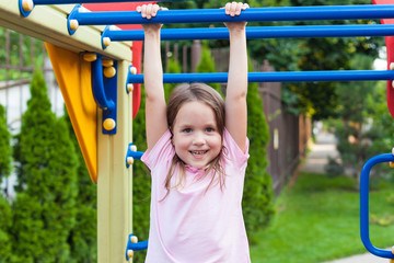 Fototapeta premium Cute little girl having fun on a playground outdoors in sunny summer day. Active healthy leisure and outdoor sport for kids. Fun activity for kid concept.