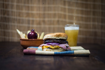 Homemade burger with cheddar, bacon, purple onion, rustic potatoes, spicy ajies beer and fire