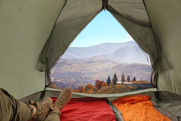 Closeup of woman in camping tent with sleeping bags on mountain hill, view from inside