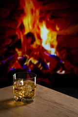 Glass of whiskey in front of a fireplace