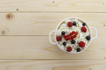 Bowl with cottage cheese and fresh berries on wooden table