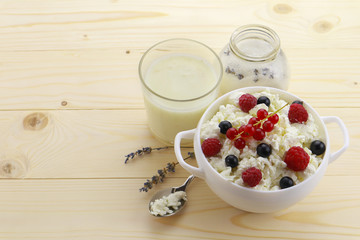 Composition with cottage cheese, fresh berries and yogurt on wooden table