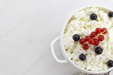 Bowl with cottage cheese and fresh berries on light background