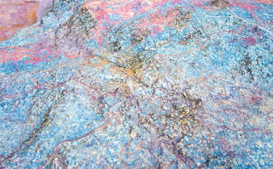 Colorful stone texture background. Big rock with colors of rainbow close up. Top view.